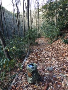 Canvas pack set down on a leaf-covered trail through rhododendron and bare hardwoods, Linville Gorge, November 2019