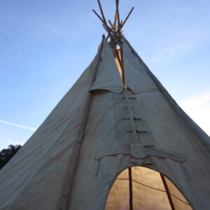 Looking up at the canvas tipi and its poles against a clear blue sky, 2014