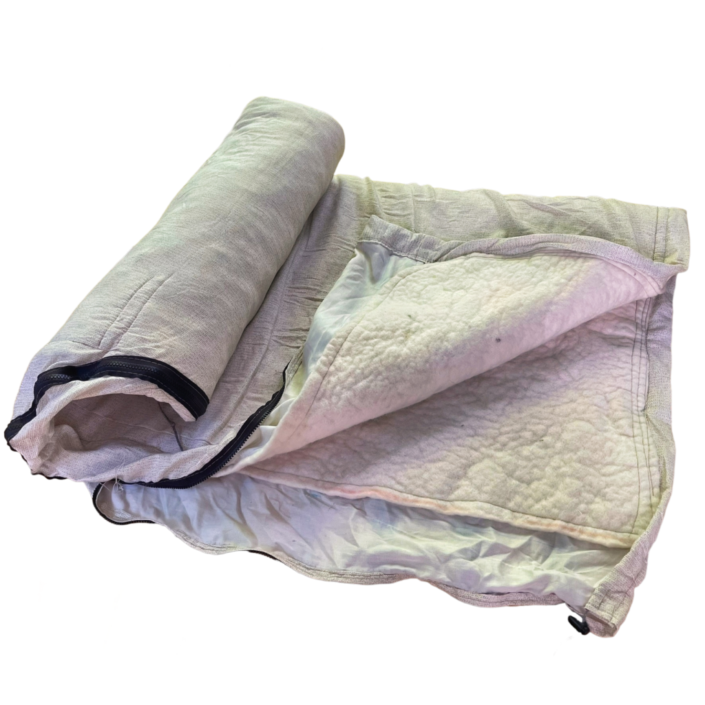 Zippered wool felt bedroll half rolled, cotton shell opened along the black full-length zipper to show the cream wool felt inside