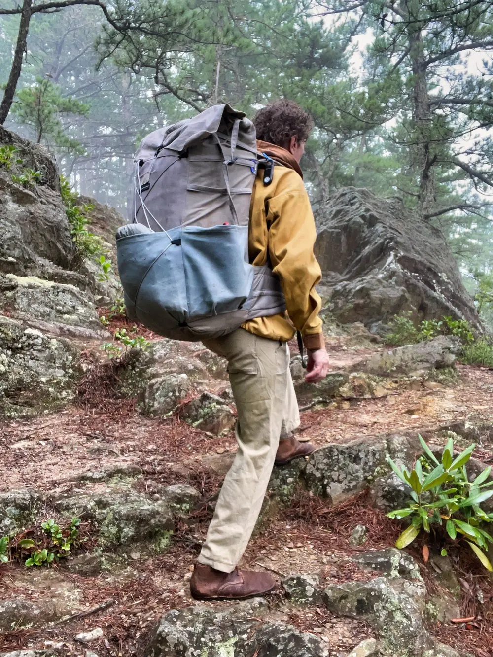 Hiker climbing a rocky trail with the Lucky Sheep organic canvas backpack